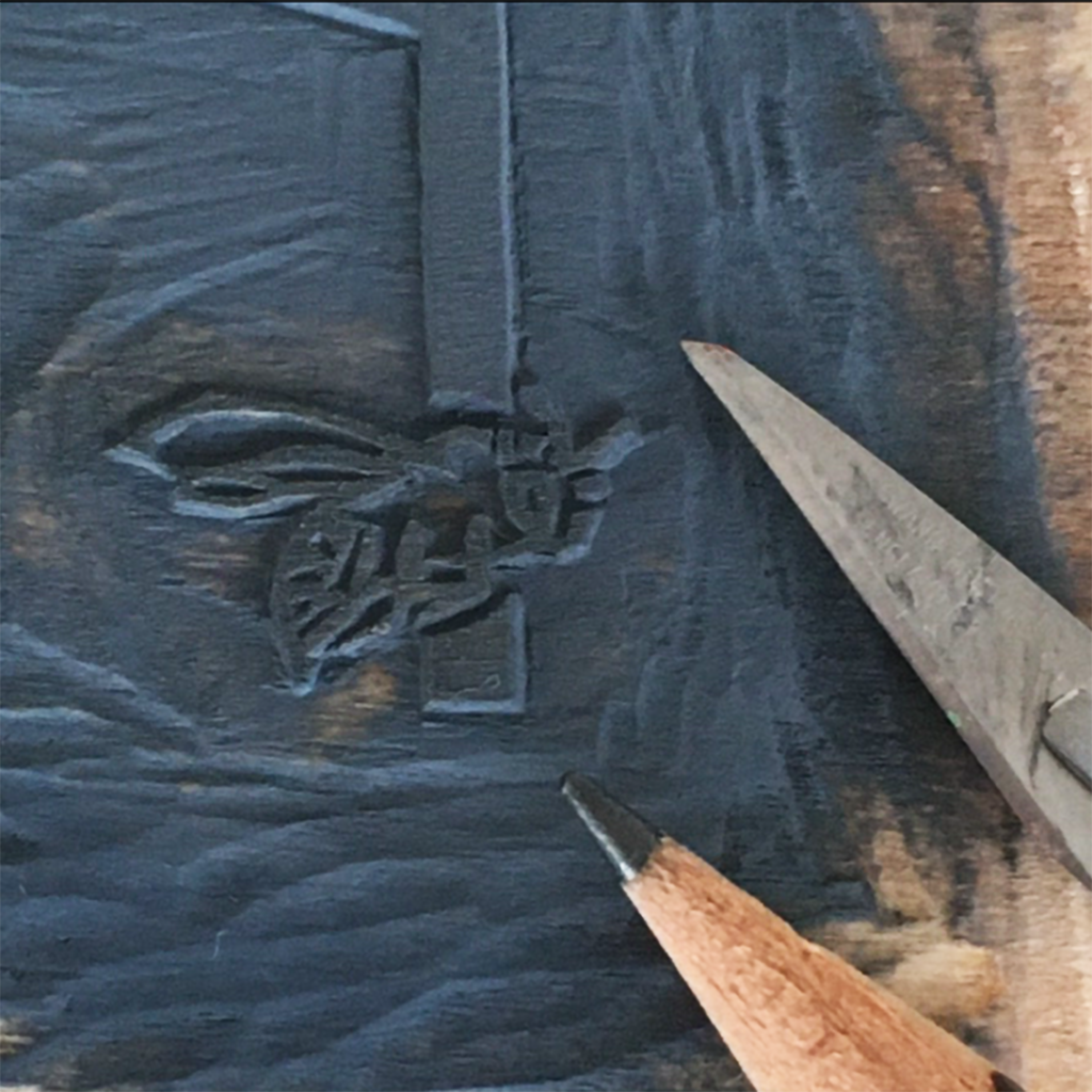 Close-up of the carved and printed bee, scalpel and pencil tip for scale