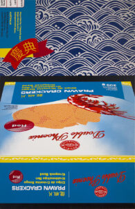 Painting of a packet of Double Phoenix prawn crackers with pattern and 'CELEBRATION' ribbon