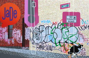 Painting of an urban back street in Melbourne highlighting graffiti and street signs; a lone dog runs down the street away from their owner