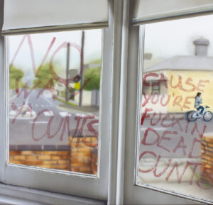 Painting of a pair of windows looking outside to the street beyond with a guy riding a bike talking on his mobile phone, in the air hangs the words that he was swearing as he rode by - they are some really rude words.