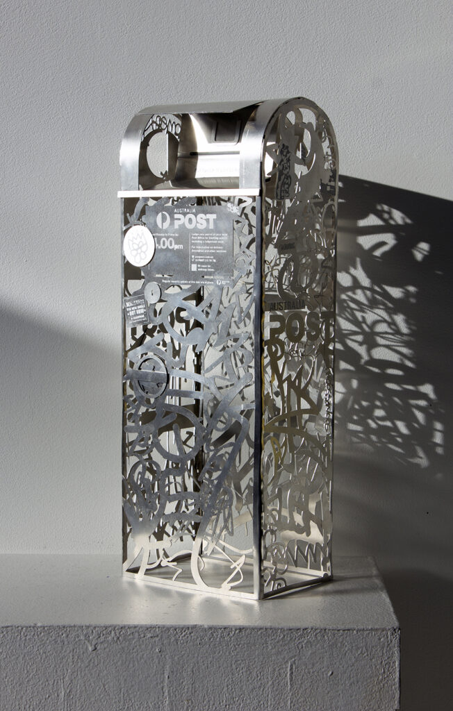 an aluminium sculpture of a mailbox completely made from tags, stickers and signage